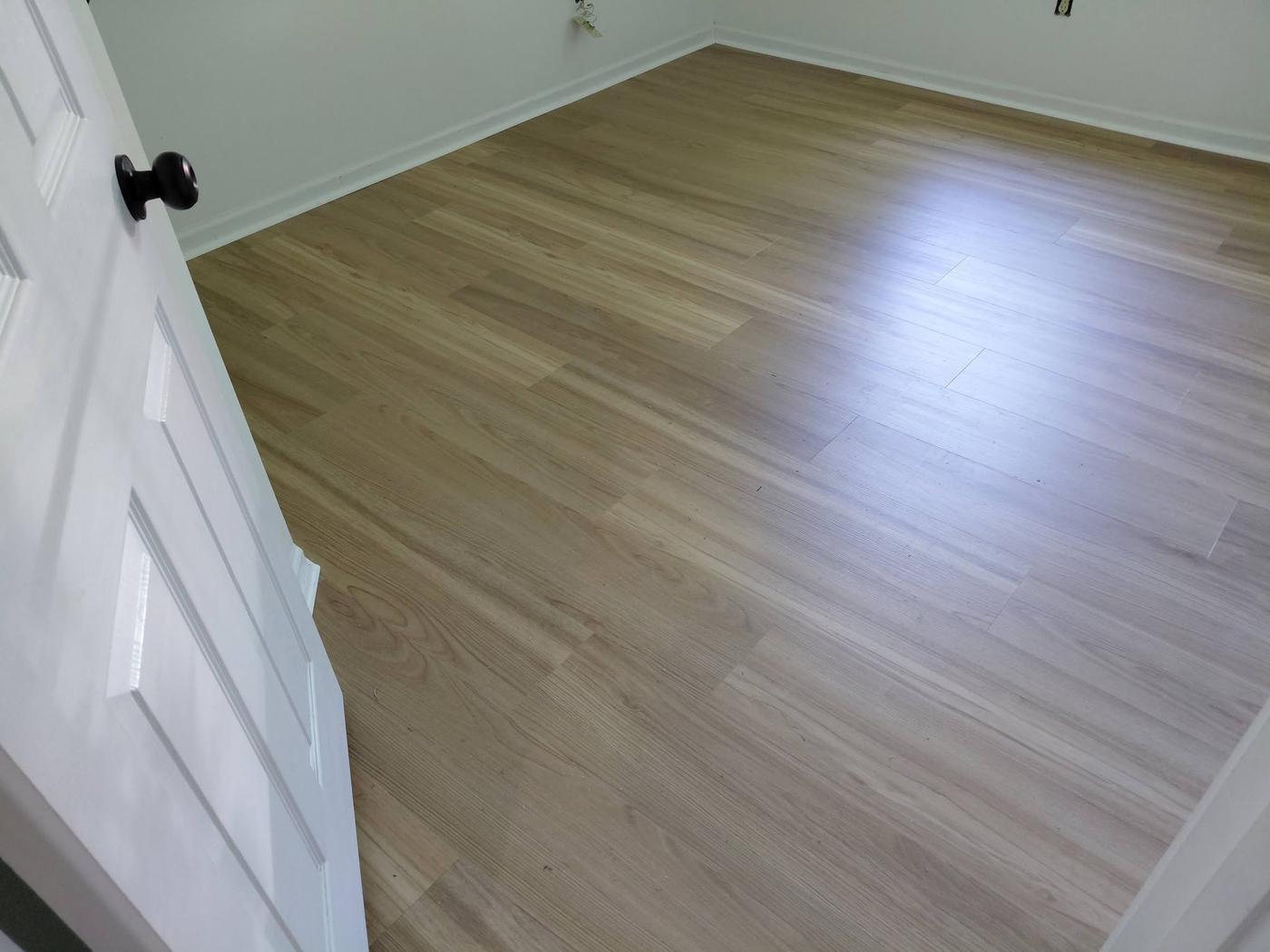 Finished plank floor in an empty room with pale walls