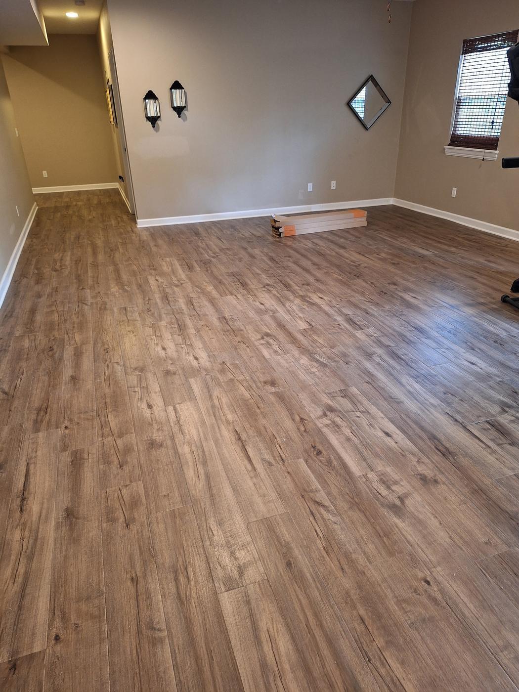 Weathered multi tone plank floor in a room with warm walls and wall sconces