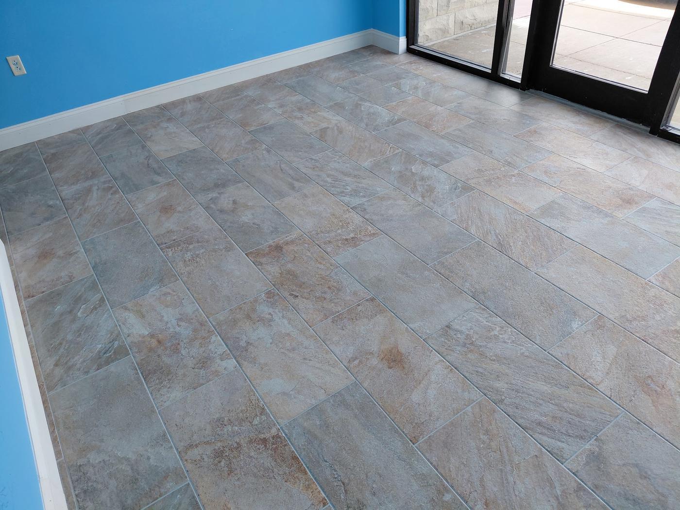 Large format stone look floor tile laid in a room with a glazed entrance